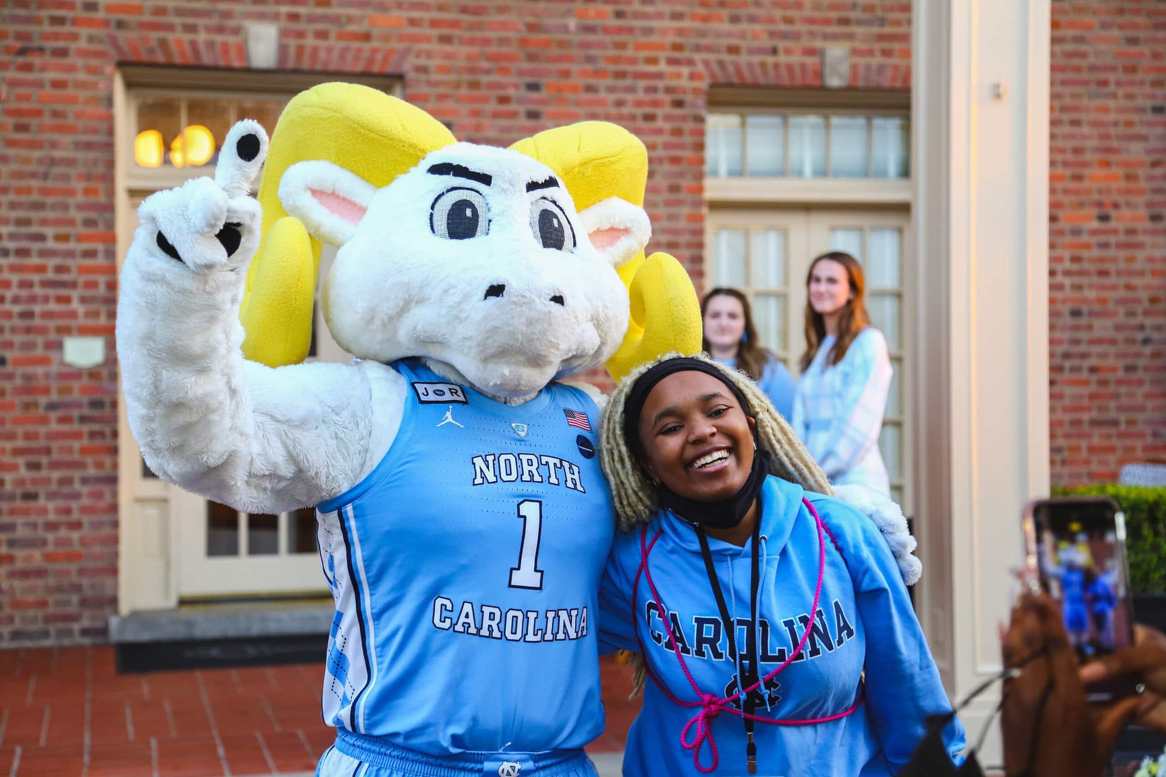 Make a Gift A woman smiling with a mascot in front of a building, creating a joyful and memorable moment
